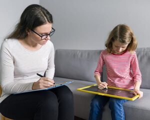 Therapist works with a young child and takes notes during their ADHD treatment