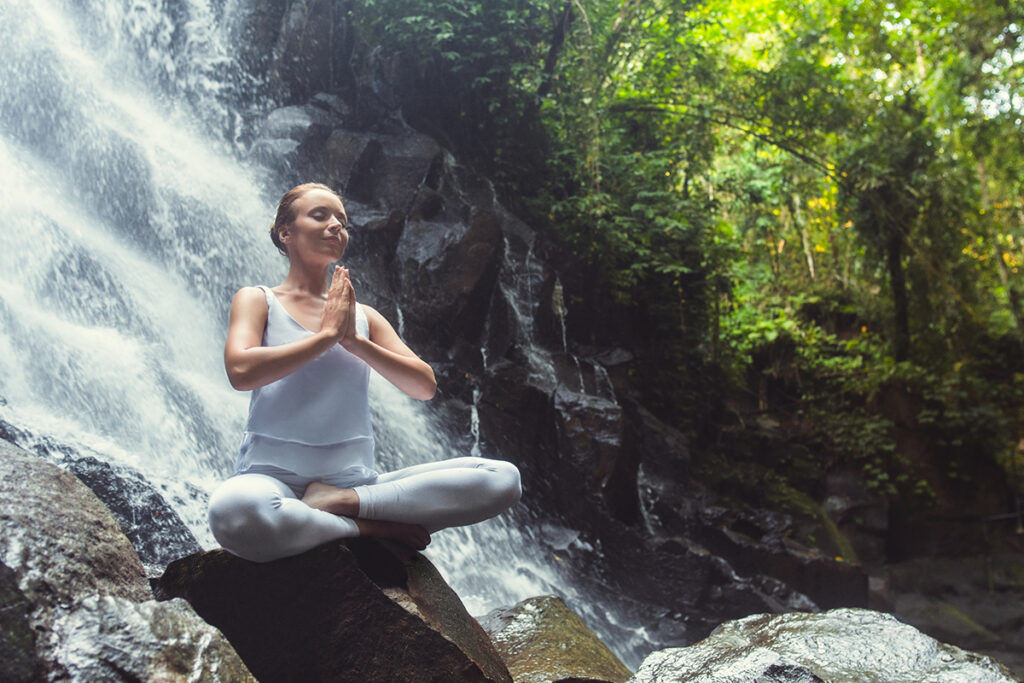 Woman doing yoga on the waterfall