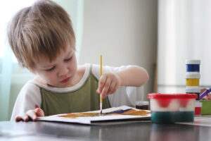 a toddler paints while in his autism spectrum disorder treatment program