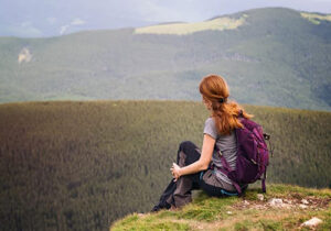 woman on hilltop overlooking beautiful forest contemplating paying for mental health services