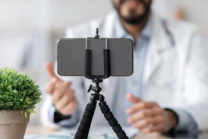 a phone is set up on a stand in front of a doctor during a telehealth therapy session as a part of several mental health telehealth services provided with virtual care