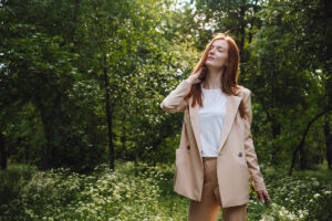 Stress and resilience. Spend Time in Nature to Reduce Stress and Anxiety. Nature break relieves stress. Young woman in suit enjoying nature and walking in green summer park