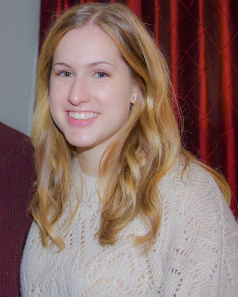 Jordan Bilich is a smiling woman with log blonde hair. She is wearing a beige cable knit sweater.