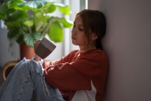 woman drinks coffee and lean against a wall and thinks about the effects of adhd in women