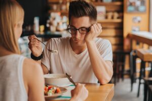 man sits at a restaurant table and is upset while trying to eat and thinks about the link between nutrition and depression