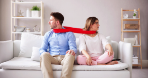 a man and a woman sit on a couch and bound by a scarf on their necks while talking to therapist about codependent relationship