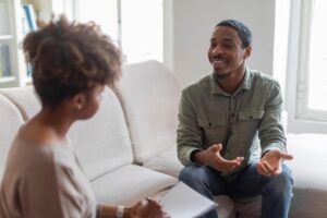 a man sits on a couch with a therapist asking her if there are psychiatry services near fox chapel