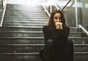 woman is outside sitting on steps and thinking about the signs of learned helplessness