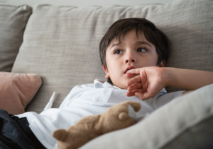 a young child sits on a couch in therapy as he is experiencing signs of anxiety in children