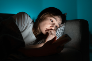 a woman sits in the dark looking on her phone realizing there might be a link between social media and depression symptoms