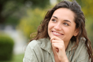 woman smiles and holds hand to her chin thinking about the benefits of spravato vs antidepressants