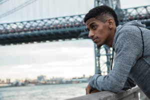 a man leans over railing near a bridge thinking about what it means to be living with ocd