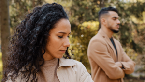 a couple stand outside away from each other and both individuals struggling with trauma and relationships