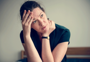 woman sits and holds her hand to her forehead while wondering about anxiety and memory loss