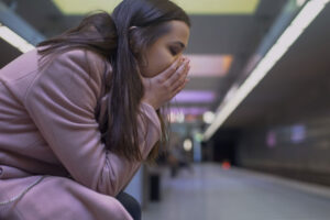 an upset women is sitting and leans down to put her hands over her mouth while struggling with prolonged grief disorder