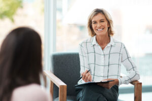 a woman with a clipboard takes notes while discussing the differences between psychiatrist vs therapist