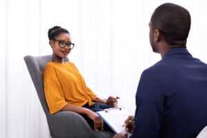a woman with glasses sits in a chair and talks to a therapist about ocd and anxiety