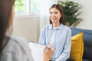 smiling woman sits on couch during her session for mental health counseling at the bloomfield office
