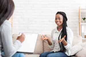 a patient is sitting on a couch and talking to therapist who is taking notes for patient about psychiatric services in the greensburg area
