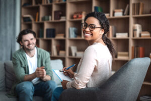 a therapist sits in a chair smiling with a patient discussing how to prepare for first therapy session