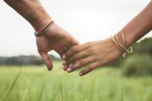 two hands holding each other in a field outside after having therapy for codependency and narcissism concerns