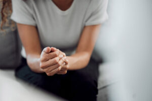 woman sits and is holding her hands together thinking about the connection between depression and laziness