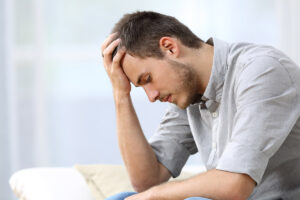 struggling man holds his hand to his forehead wondering if he has clinical depression