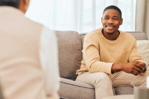 smiling man sits on couch during his ocd therapy at pittsburgh location