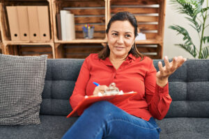 woman therapist sits on a couch with a clipboard talking about mental health services in pittsburgh