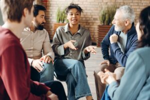 five people sit together in a circle during their group therapy session