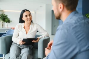 smiling woman with tablet in hand talks to person about benefits of therapy