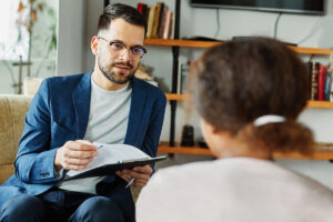 Therapist with clipboard speaking to patient