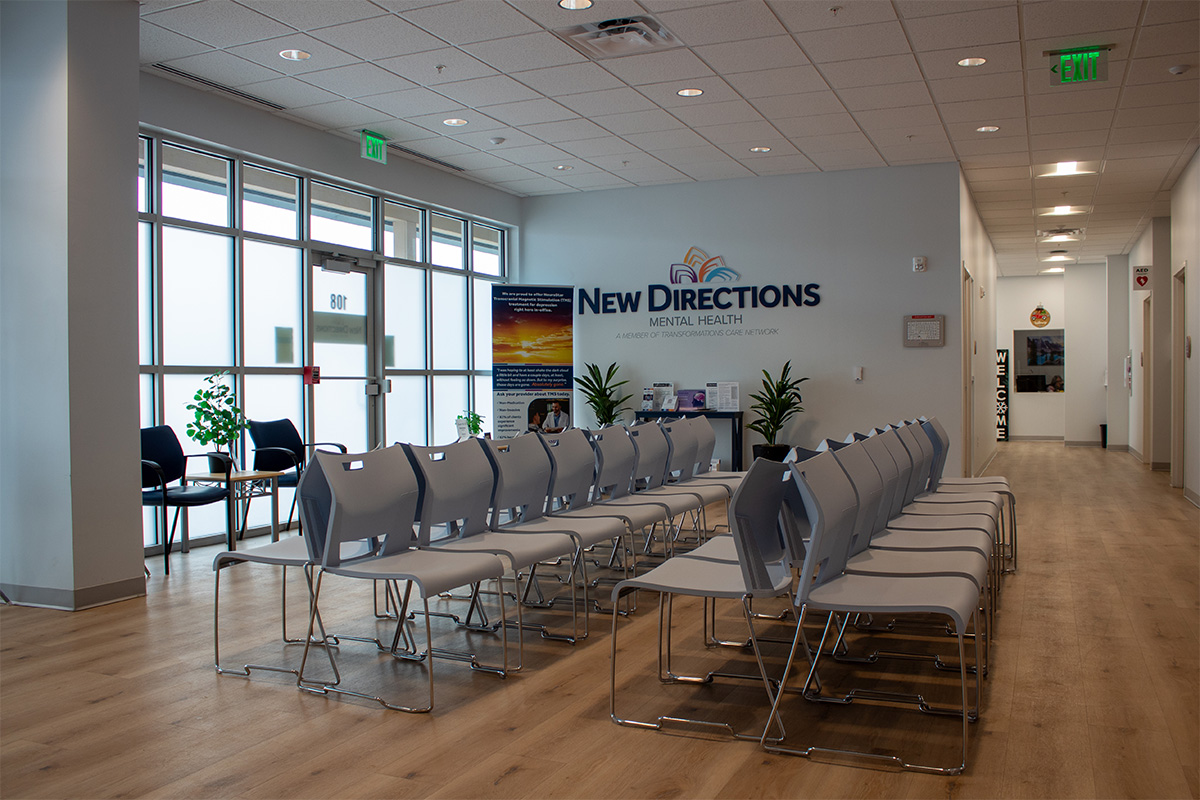 Indoor New Direction sign on wall behind rows of chairs in waiting room